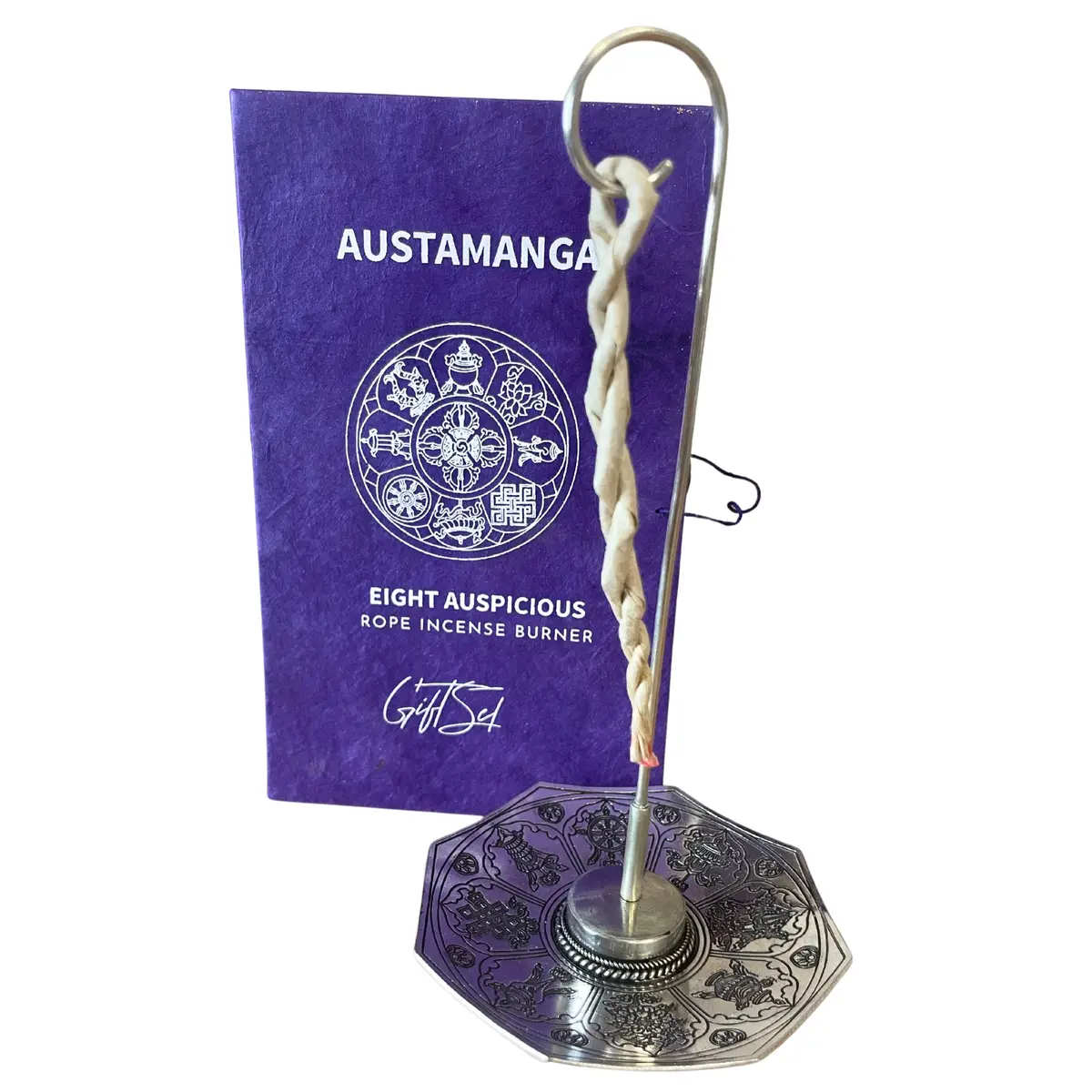 Set med silverpläterad rökelsehållare och reprökelse framför dekorativ ask med Astamangal-symbol