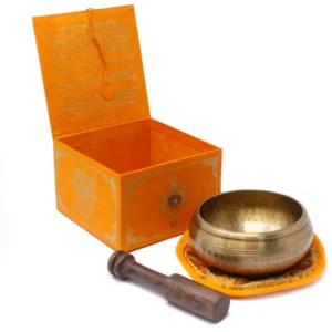 Tibetansk klangskål med träklubba och orange förvaringsbox