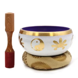 Stor tibetansk klangskål med vit yta och guldfärgade Yin & Yang-symboler, lila insida, träklubba och kudde