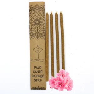 Fyra stora rökelsestickor av Palo Santo bredvid ett dekorativt kraftkuvert och rosa blommor