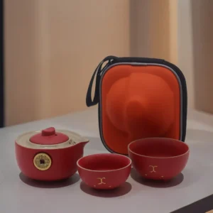 Rött tekannaset med två koppar och orange resefodral
