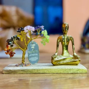 Handgjort träd av ädelstenar med gyllene yogafigur i mudra på mangoträbas