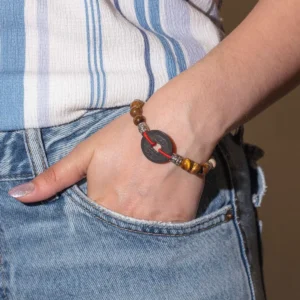 Hand med Tri Hita Karana-armband med runda pärlor och röd tråd