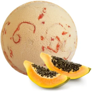 Rund badbomb med inslag av röd färg och två skivor papaya framför