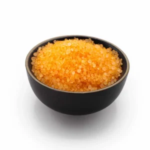 Orange doftgranulat i svart skål på vit bakgrund