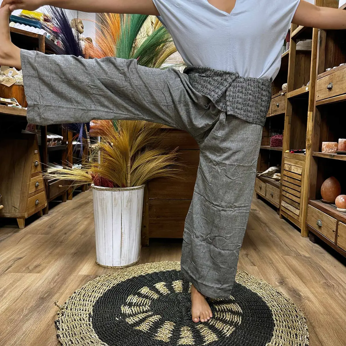 Person som utför yogaposition iklädd grå yoga- och festivalbyxor med mandalamönster på midjebandet