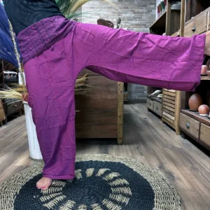 Person som bär lila yoga- och festivalbyxor med mandalamönster i ett rum med träinredning