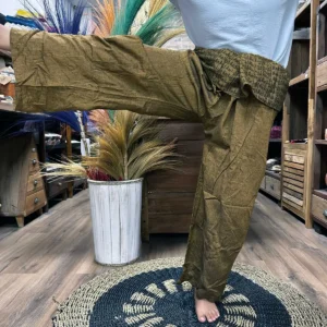 Person som bär lösa yoga- och festivalbyxor med mandalamönster i orange i en inomhusmiljö