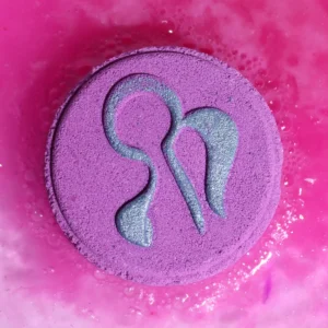 Lila rund badbomb med Jungfruns stjärntecken i silver på rosa vatten