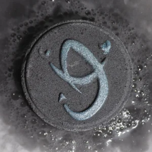 Svart badbomb med blått skorpion-symbol i badvatten