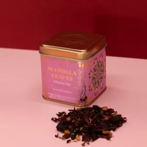 Dekorativ rosa och guldfärgad plåtburk med fruktigt örtte och löste bredvid
