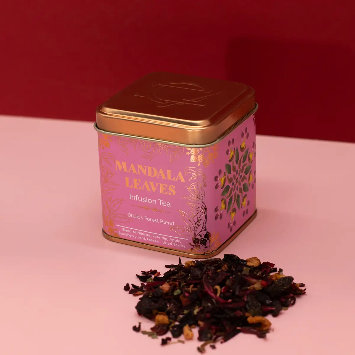 Dekorativ rosa och guldfärgad plåtburk med fruktigt örtte och löste bredvid