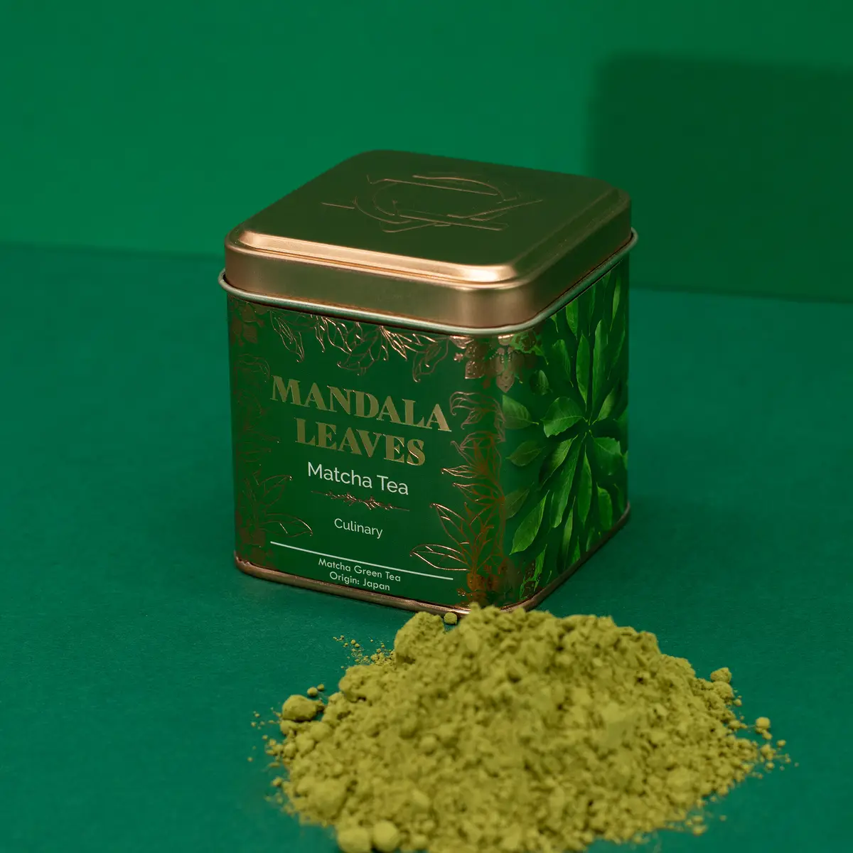 Grönt matchapulver framför en grön och guldfärgad burk med texten Mandala Leaves Matcha Tea Culinary