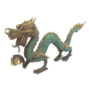 Handgjord mässingsfigur föreställande en drake med grön patina och en kula
