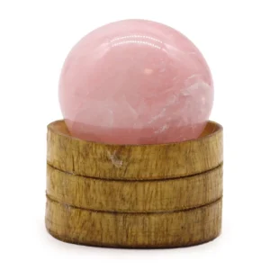 Rund rosa kristallsfär av rosenkvarts på en träställning