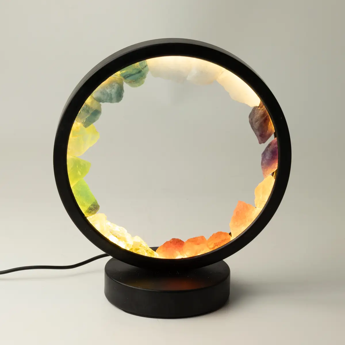 Rund lampa med svart ram och sju färgade naturliga ädelstenar i cirkel