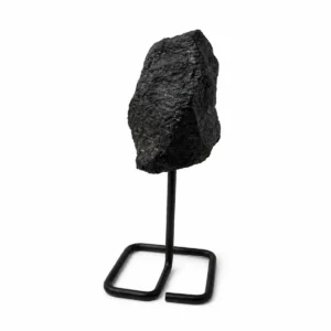 Svart turmalin mineralprov med rå yta på svart metallställning