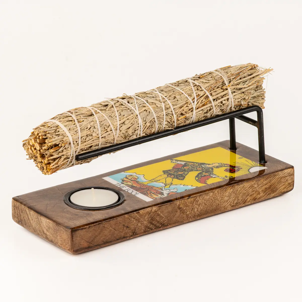 Stor emaljerad värmare i trä med metallställ och tarotmotiv The Fool, med en salviapinne ovanpå